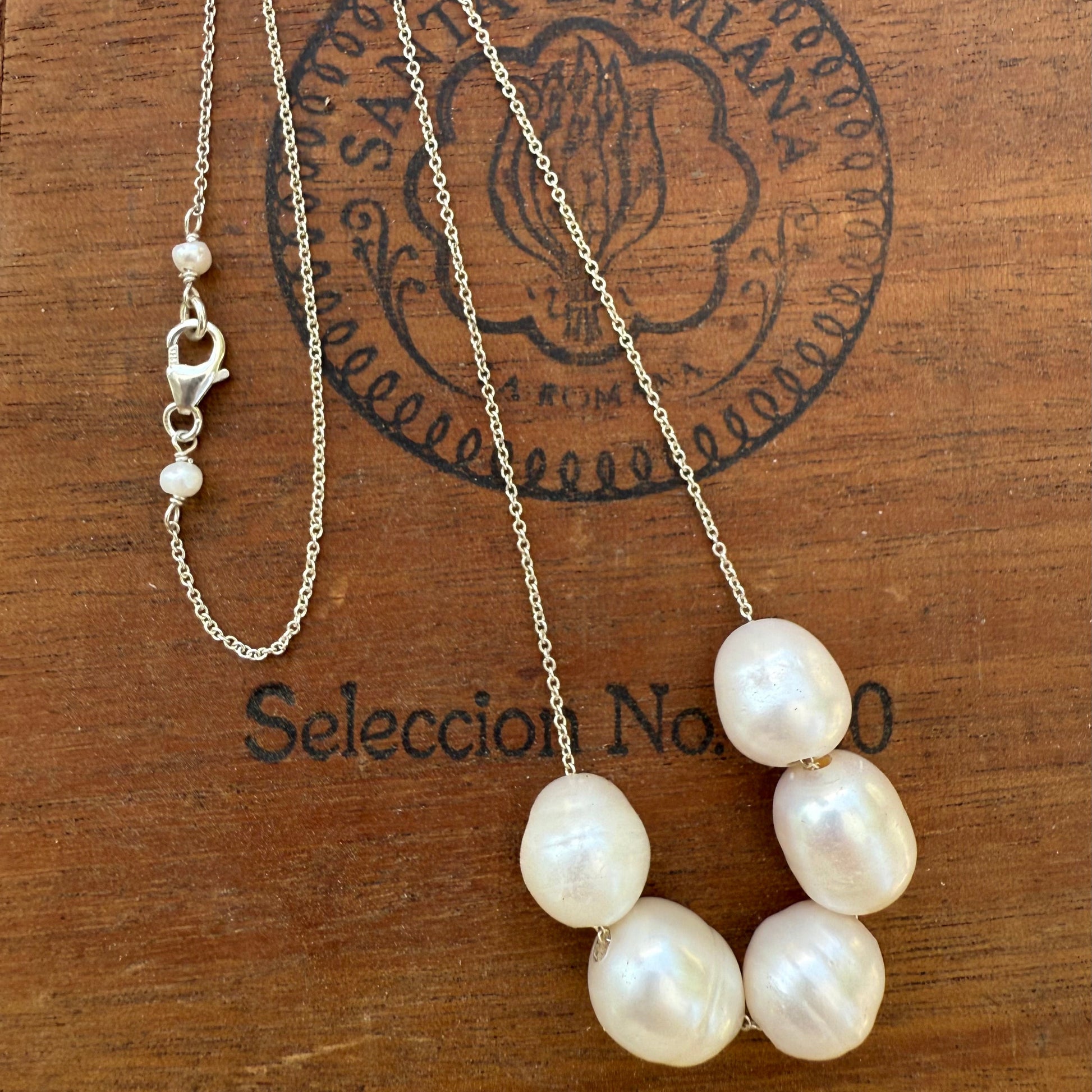 Pearl necklace on a wooden surface with 'Seleccion Nacional' branding.