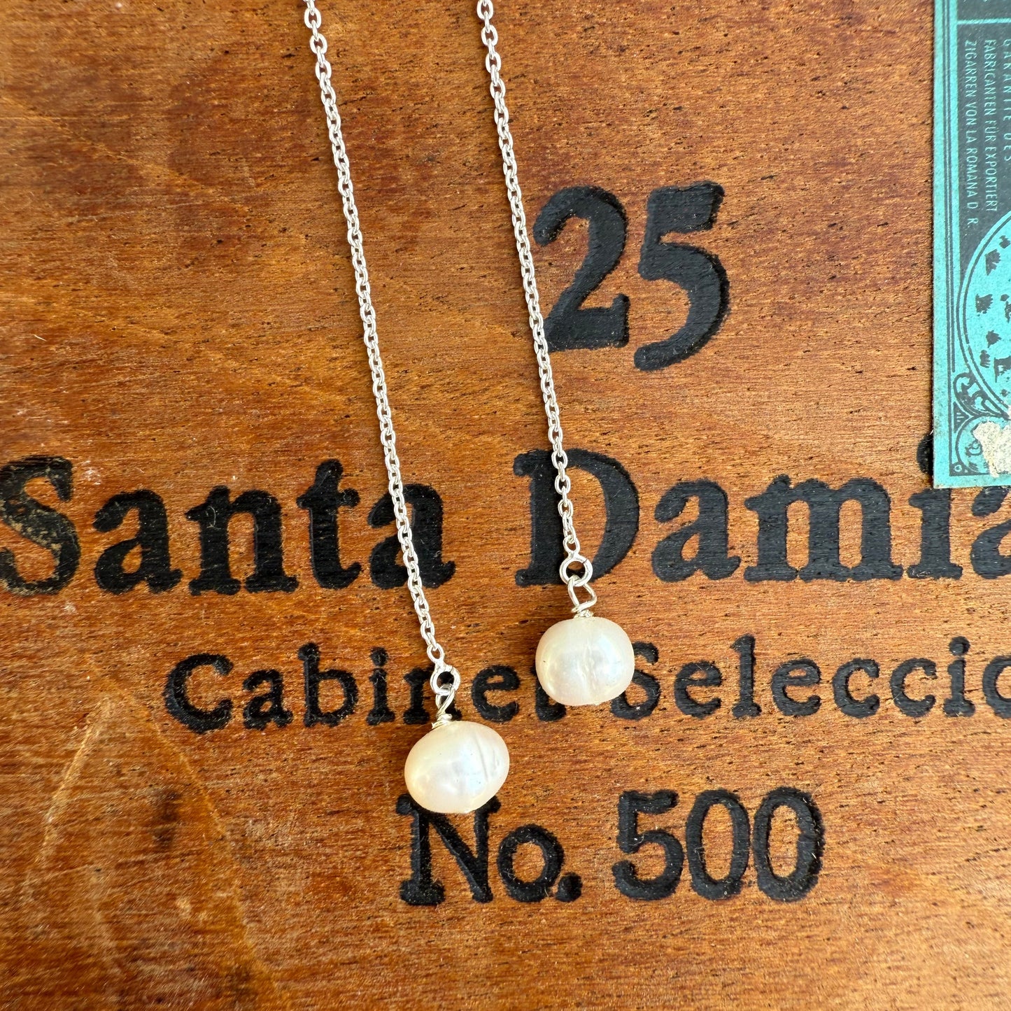 Pearl necklace on a wooden surface with 'Santa Damian' branding.