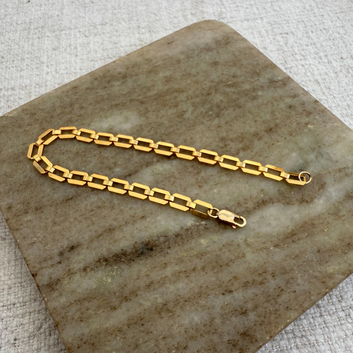 Gold chain necklace on a stone surface
