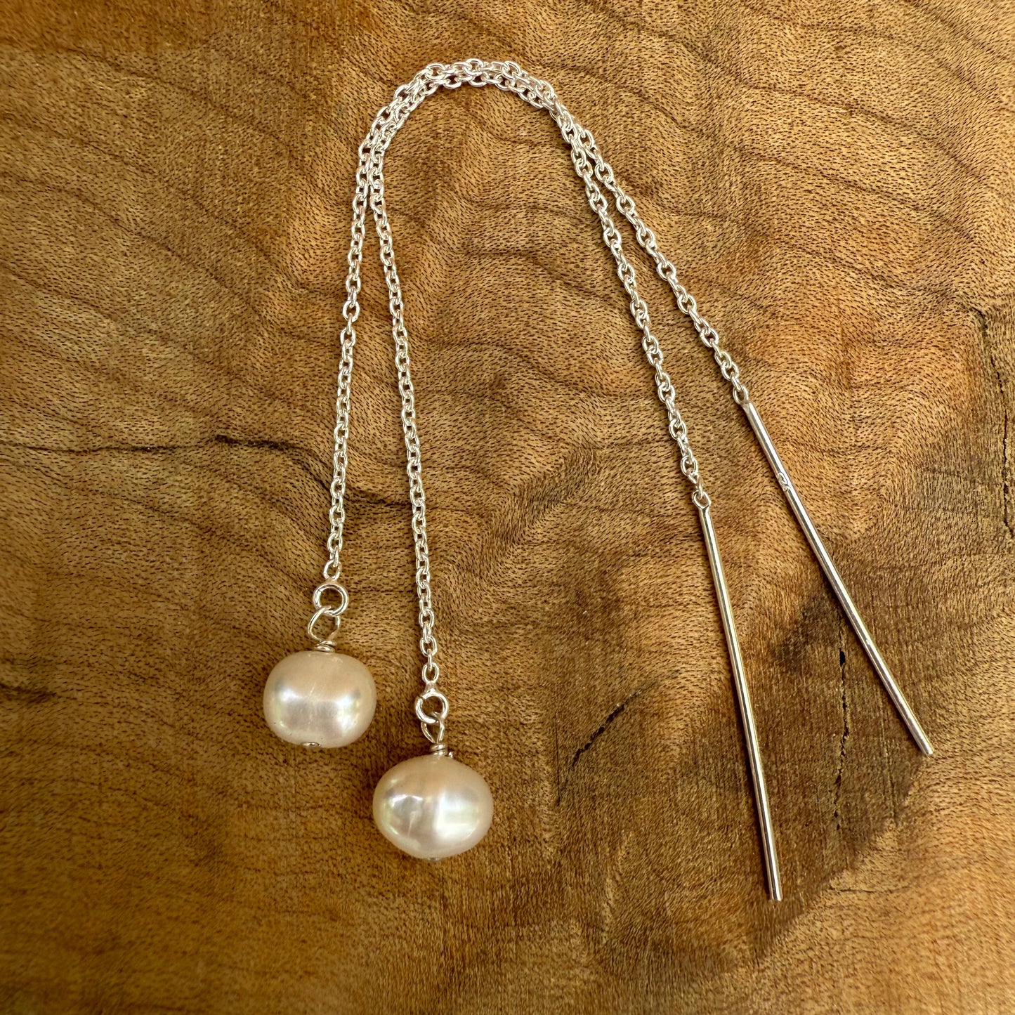 Pearl silver threader earrings on a wooden surface