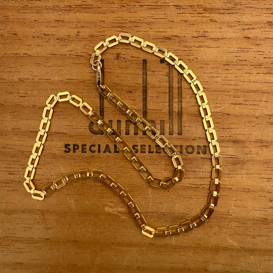 Gold chain on a wooden surface with visible branding.