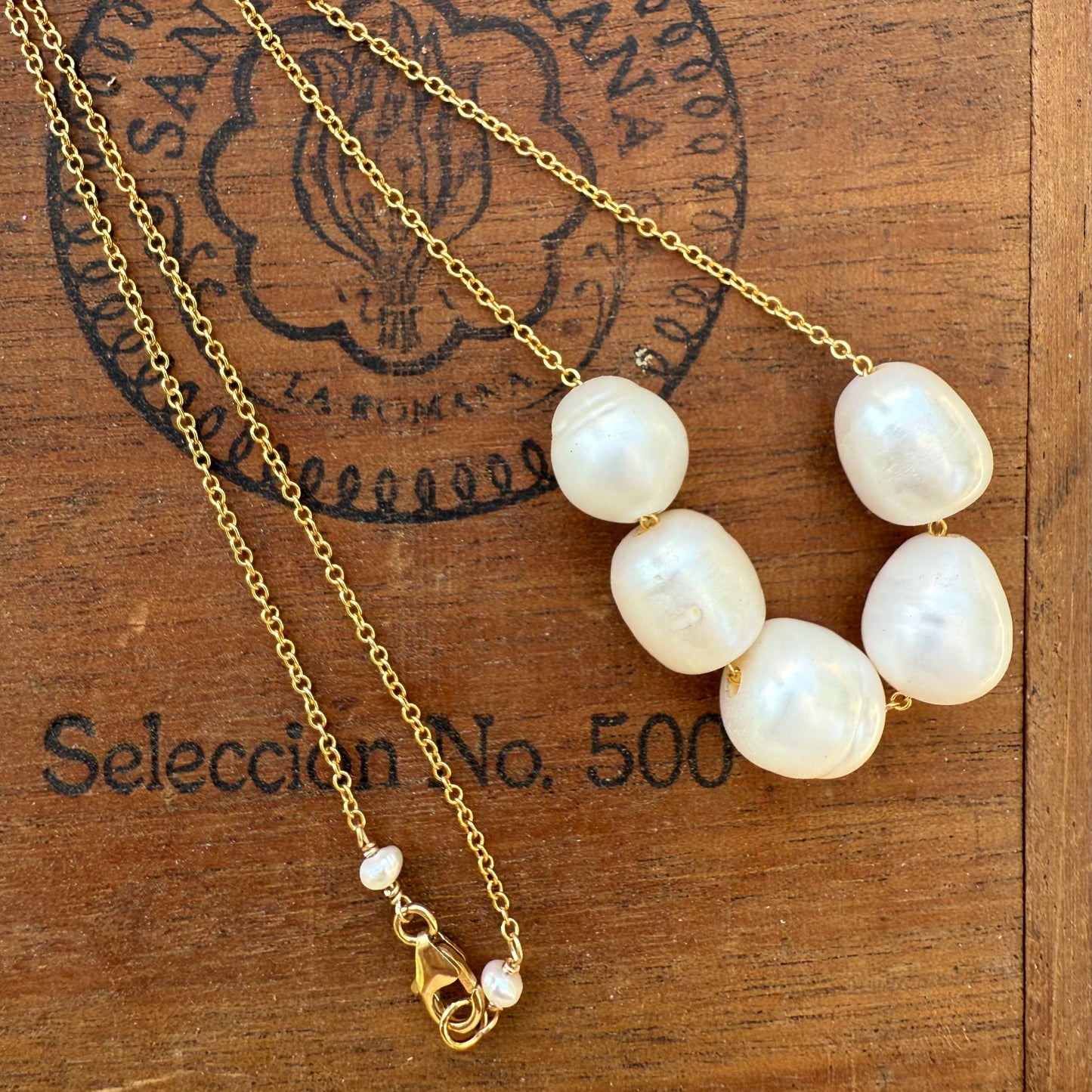 Pearl necklace with gold chain on a wooden surface