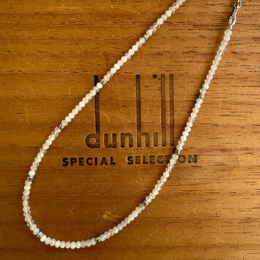 Beaded necklace on a wooden surface with Dunhill branding
