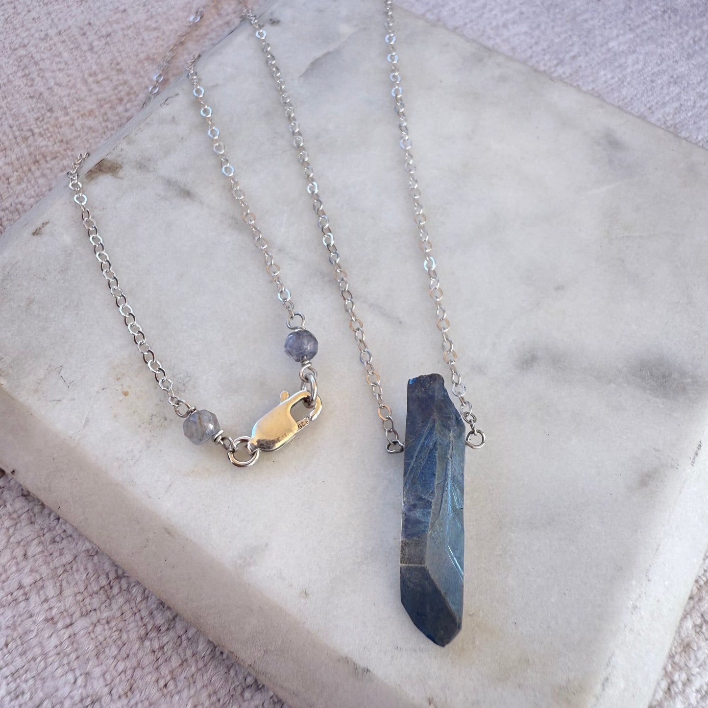 Necklace with a blue crystal pendant on a marble surface