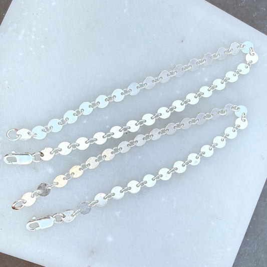 Two silver chain necklaces on a white stone surface