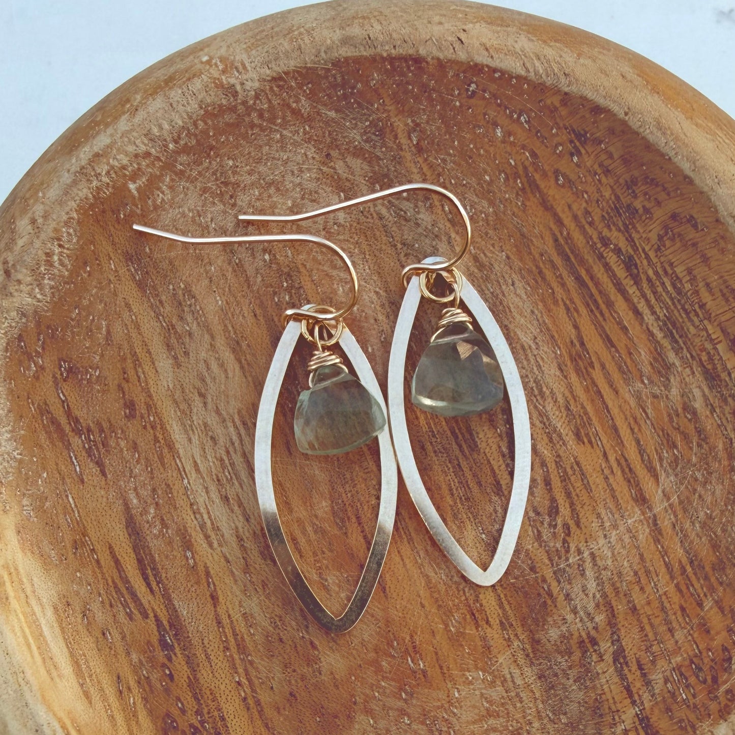 Pair of gold marquis earrings on a wooden surface with green fluorite gemstones