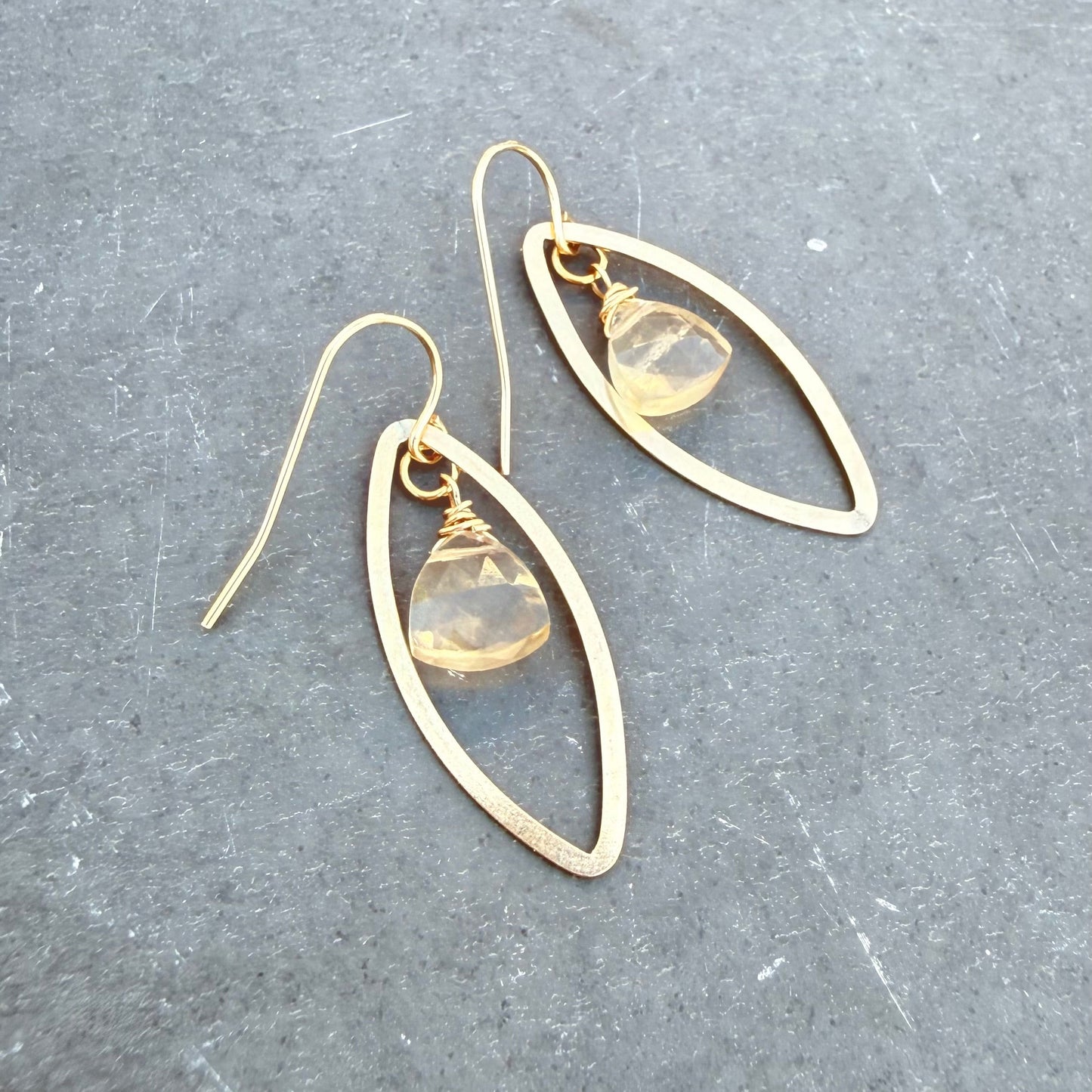 Gold filled earrings with yellow fluorite trillion stones on a gray surface