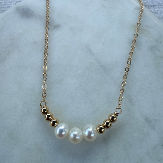 Gold necklace with pearls on a marble surface
