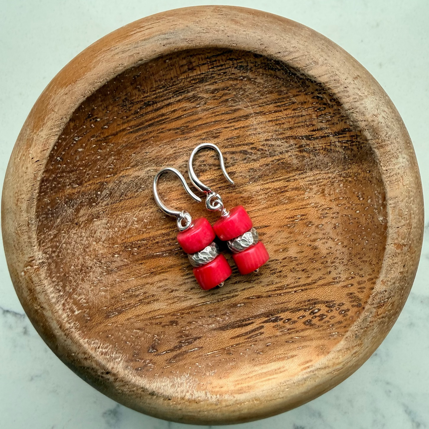 Double stack coral beads with Thai silver bead between on wood base.