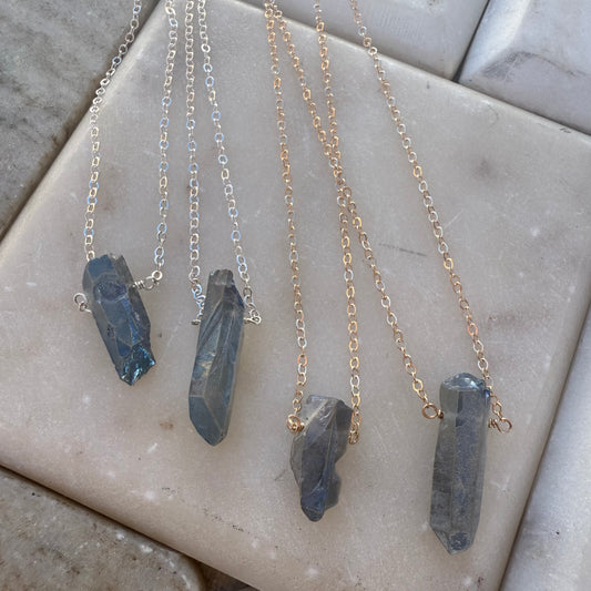Four necklaces with quartz pendants on a marble surface