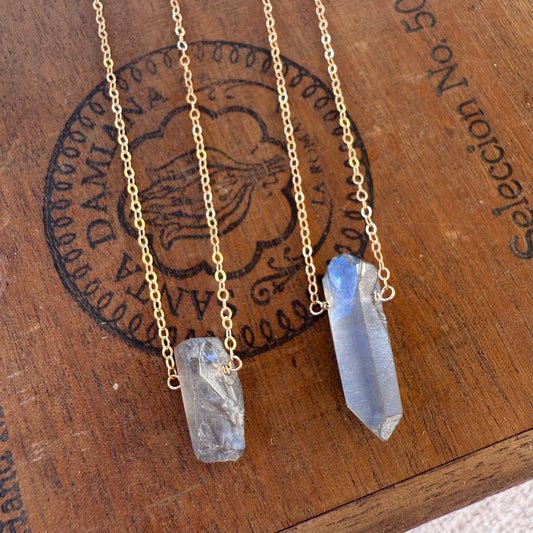 Two crystal necklaces on a wooden surface with a vintage stamp.