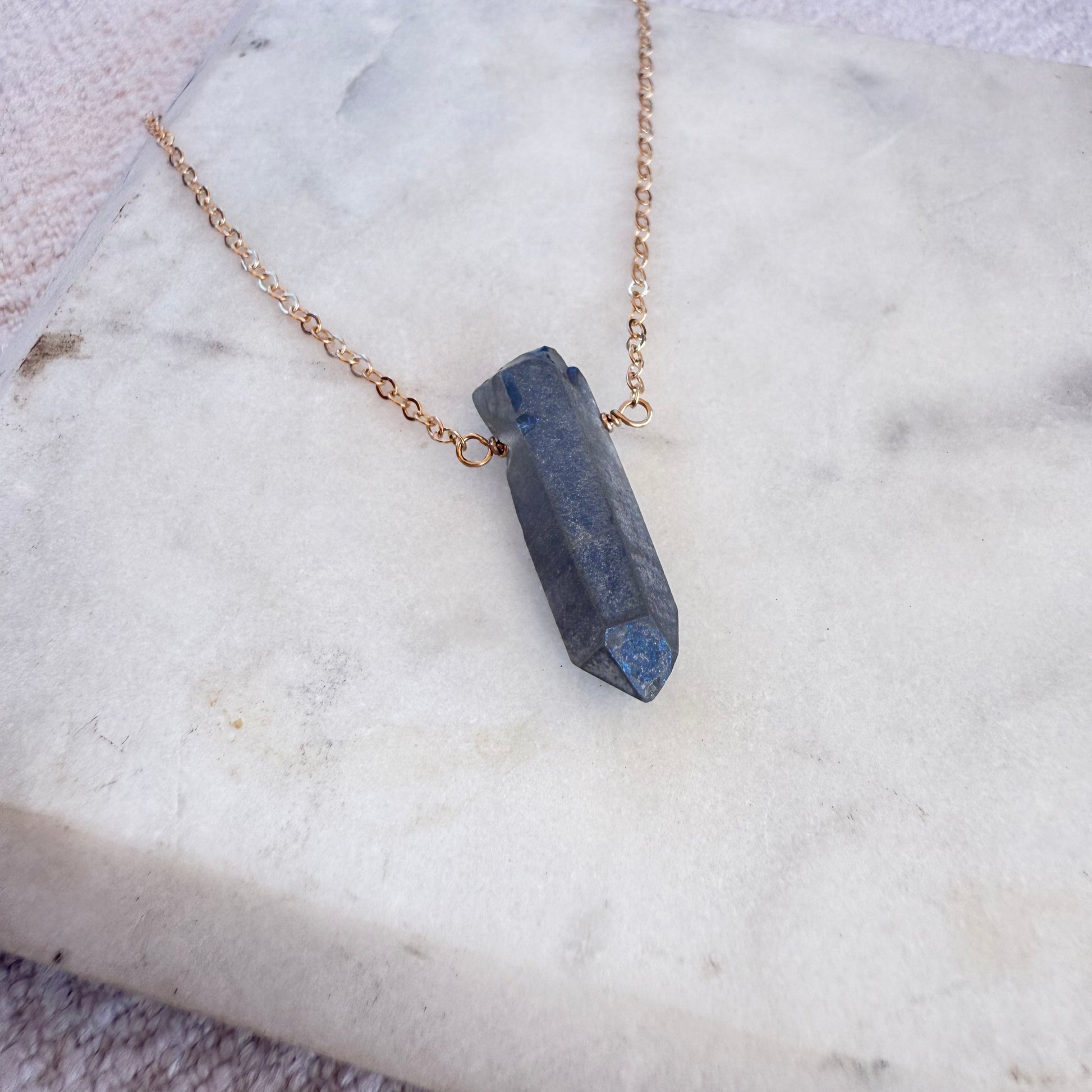 Necklace with a blue stone pendant on a marble surface